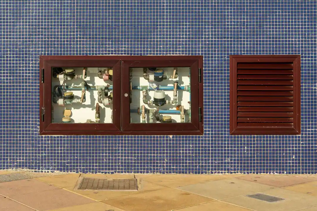 Batería de contadores de agua tras unas puertas de cristal en la fachada de un edificio de Gran Canaria
