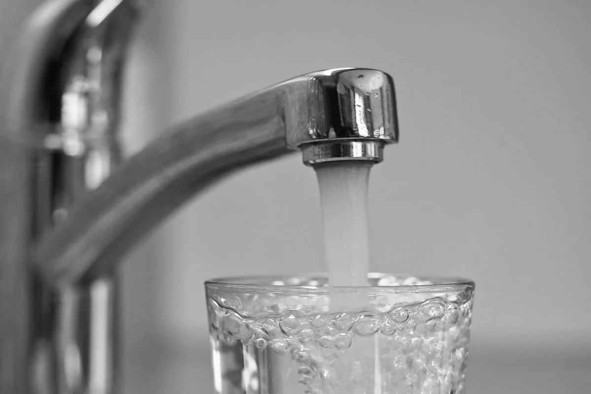 Vaso llenándose con agua del grifo, en blanco y negro