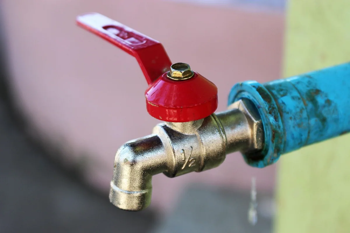 Llave de bola con palanca roja en una tubería de agua, como las que se cierran para cortar el agua en una urgencia